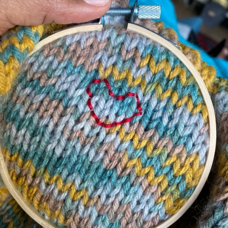 An embroidered heart on the back of a hand knit sweater